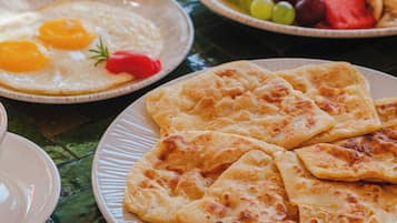 Un desayuno con platos de comida, entre ellos huevos, tostadas y fruta.
