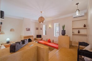 A modern living room with a sofa, a coffee table, and a TV. - Hotel Dar 55 Berbere House & Spa (Marrakech)