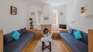 Un salon avec deux canapés, une cheminée, un téléviseur et un luminaire fixé au mur.