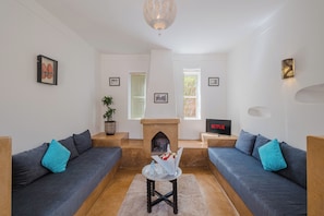 Un salon avec deux canapés, une cheminée, un téléviseur et un luminaire fixé au mur.