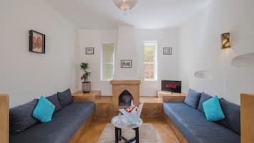 Ein Wohnzimmer mit zwei Sofas, einem Kamin, einem Fernseher und einer Wandleuchte.