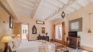 Une chambre à coucher avec un lit, des lampes de chevet, une télévision, une armoire en bois et un tapis à motifs.