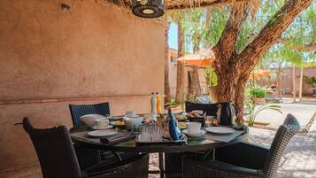 An outdoor dining area with wicker chairs, a round table, and a thatched roof.