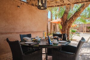 An outdoor dining area with wicker chairs, a round table, and a thatched roof. - Hotel Dar 55 Berbere House & Spa (Marrakech)