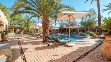 A poolside area with lounge chairs, umbrellas, and a palm tree.