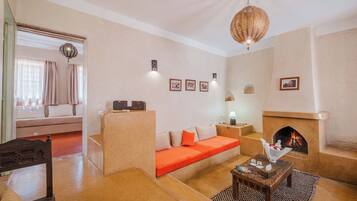 A living room with a sofa, a coffee table, a fireplace, and a hanging light fixture.