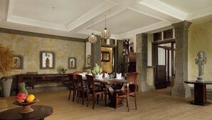 A dining area with a wooden table and chairs, a stone wall, and a staircase. - 5 Bedroom Villa in Ubud with Jungle view (Ubud)