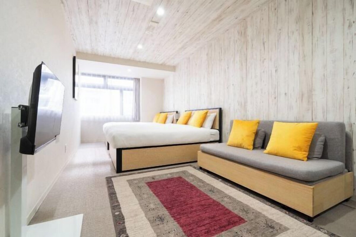 A modern bedroom with a bed, sofa, and a TV.