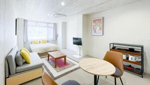 Ein modernes Hotelzimmer mit einer Couch, einem Bett, einem runden Tisch und einem Fernseher.