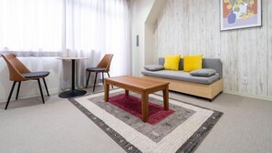 Ein modernes Wohnzimmer mit einer Couch, zwei Sesseln, einem Couchtisch und einem Teppich.