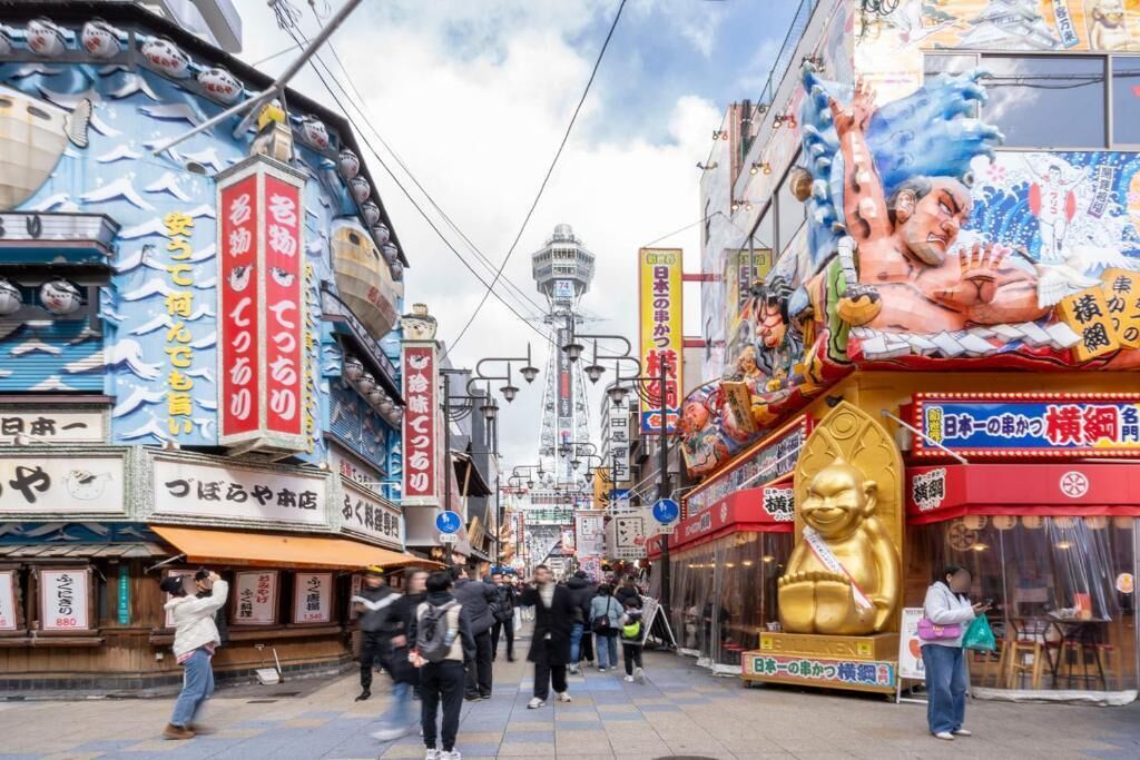 A bustling street with traditional Japanese signage and a large golden statue.