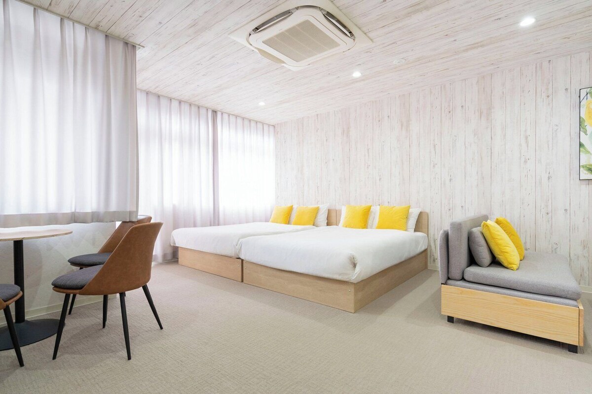 A modern hotel room with a bed, a sofa, a desk, and a chair.