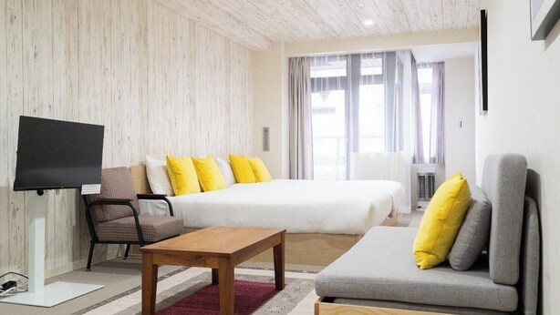 Ein modernes Hotelzimmer mit Bett, Sofa, Fernseher und Holzboden.