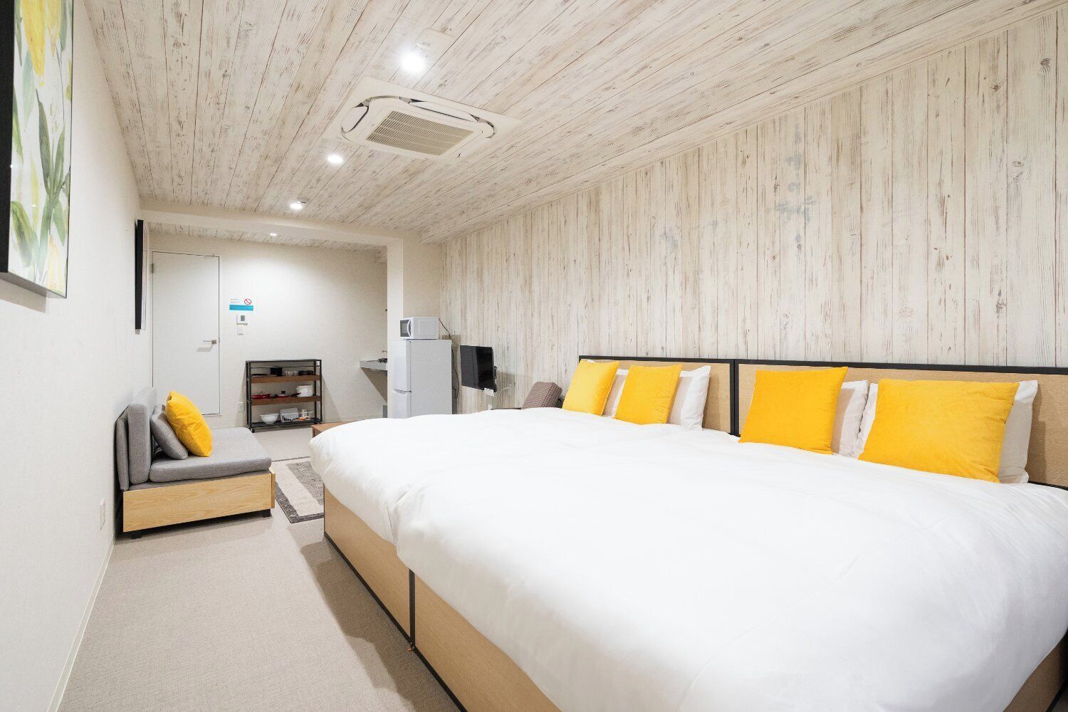 Une chambre moderne avec un grand lit, un canapé, une télévision et un coin cuisine.
