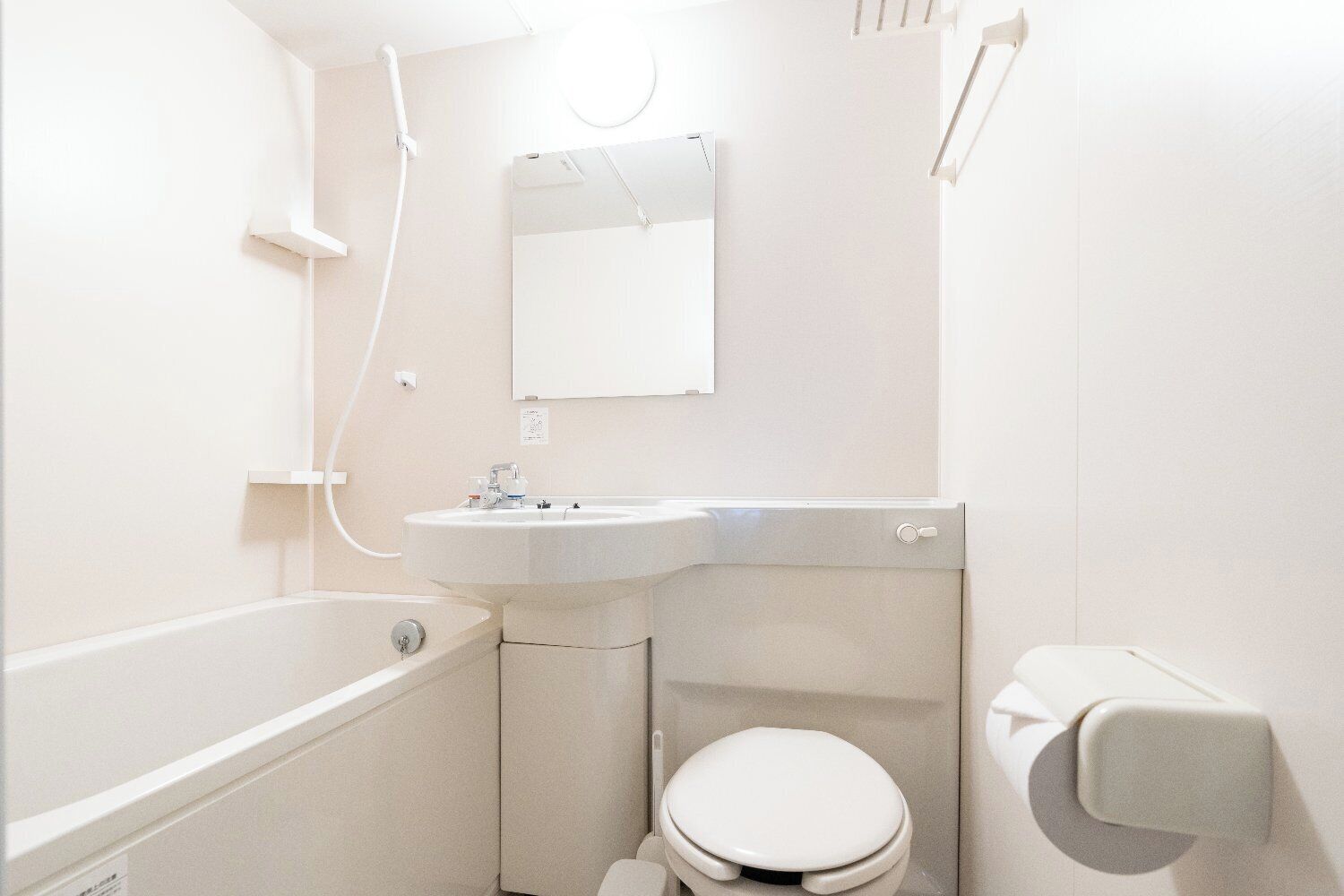 Un baño pequeño y moderno con lavamanos, inodoro y bañera blancos.