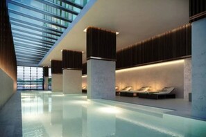 A modern indoor pool area with a glass ceiling, seating along the walls, and a clean, minimalist design. - Prime 2BR CBD | Walk Everywhere | Pool + Gym (Melbourne)