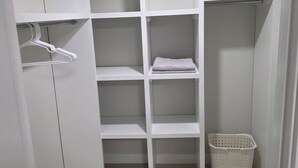A walk-in closet with white shelving, a hanging rod, and a laundry basket. - Elegant 2 Bedroom Suite - High-End Comfort! (Calgary)