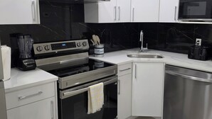 A modern kitchen with white cabinets, a black stove, a microwave, and a dishwasher. - Elegant 2 Bedroom Suite - High-End Comfort! (Calgary)