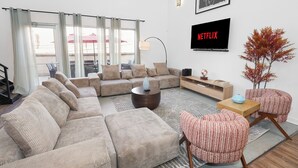 Ein Wohnzimmer mit einer Eckcouch, einem Couchtisch, einem Fernseher und einer Pflanze.