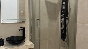 Une salle de bain moderne avec une douche à parois de verre, un lavabo sur pied noir, un meuble-lavabo en bois et des toilettes.