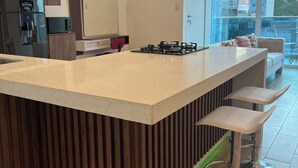 Une cuisine moderne dotée d’un îlot central, d’appareils électroménagers en acier inoxydable et offrant une vue sur l’extérieur.