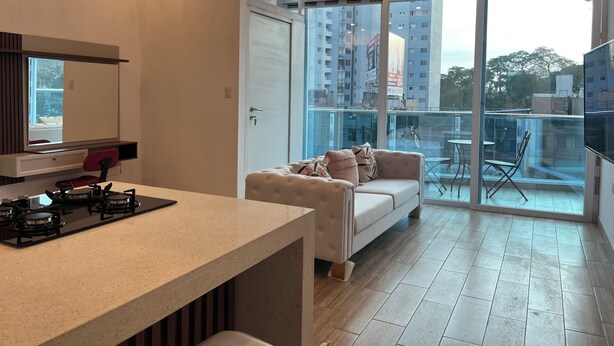 Un appartement moderne doté d’une cuisine, d’un canapé et d’un balcon offrant une vue sur la ville.