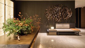 Interior moderno com uma receção de madeira, área de estar com um banco estofado e uma escultura abstrata fixada na parede.