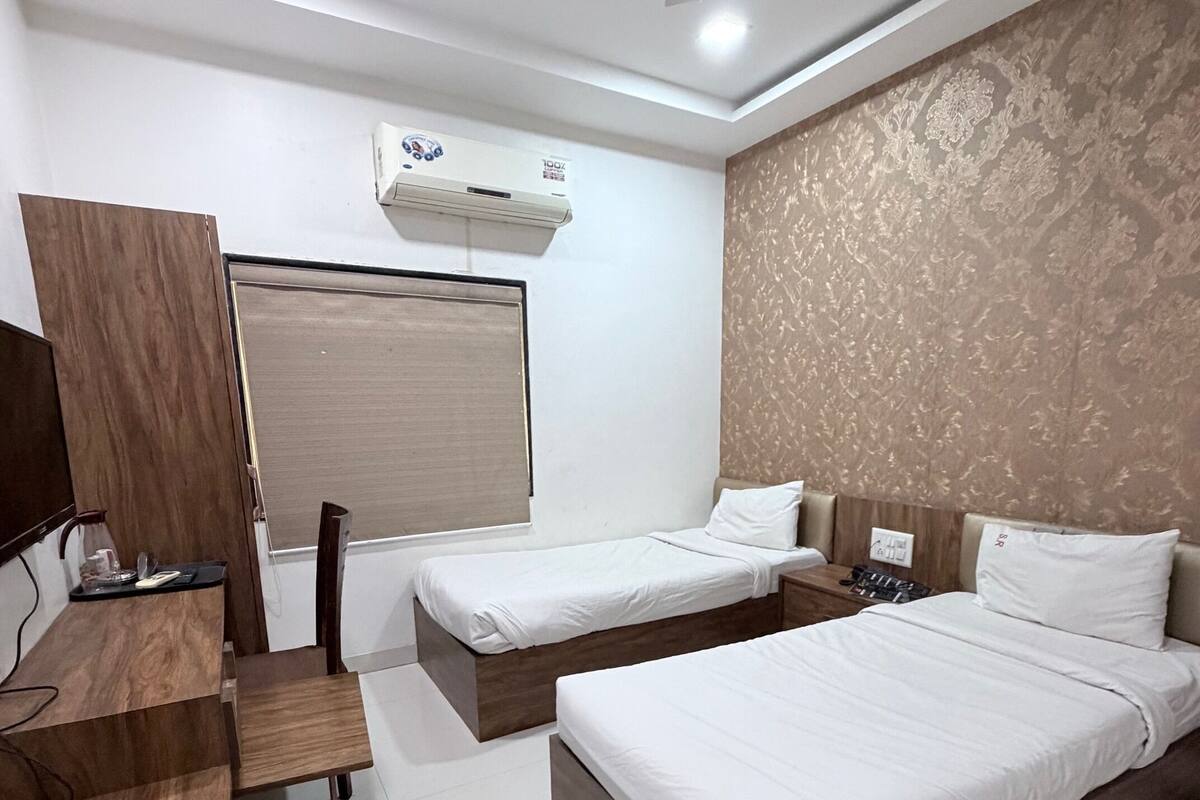 A hotel room with a bed, a desk, a chair, a wardrobe, and a ceiling fan.