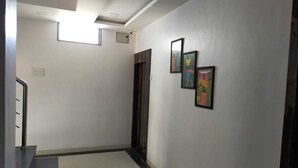 A hallway with a staircase, a door, and three framed pictures on the wall. - Hotel SR Executive Akola (Akola)