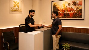 A hotel reception area with a reception desk, a couch, and a framed painting on the wall. - Xenious Smart Suites Greater Noida (Greater Noida)