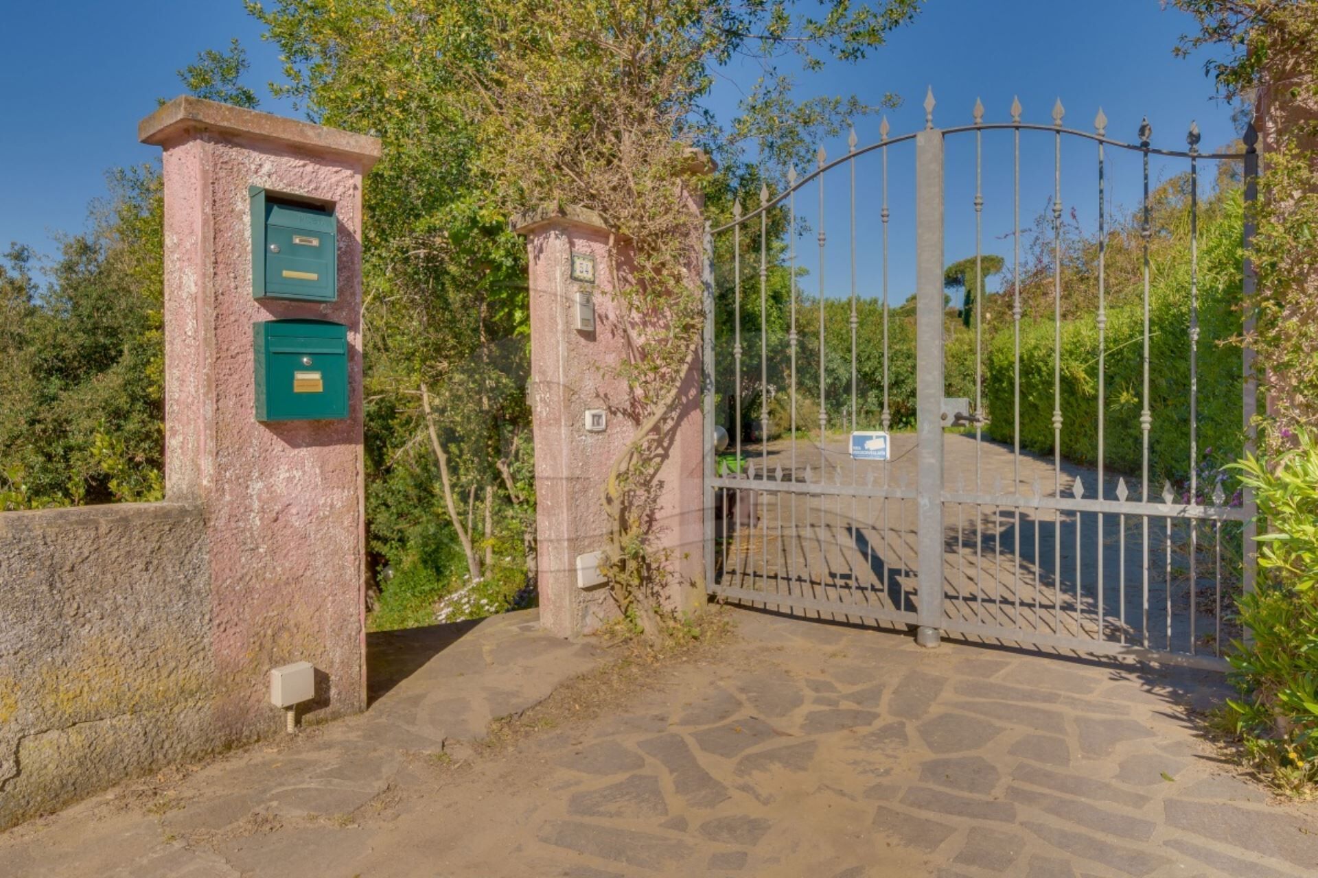 A gated entrance with a stone pathway leading to a building.