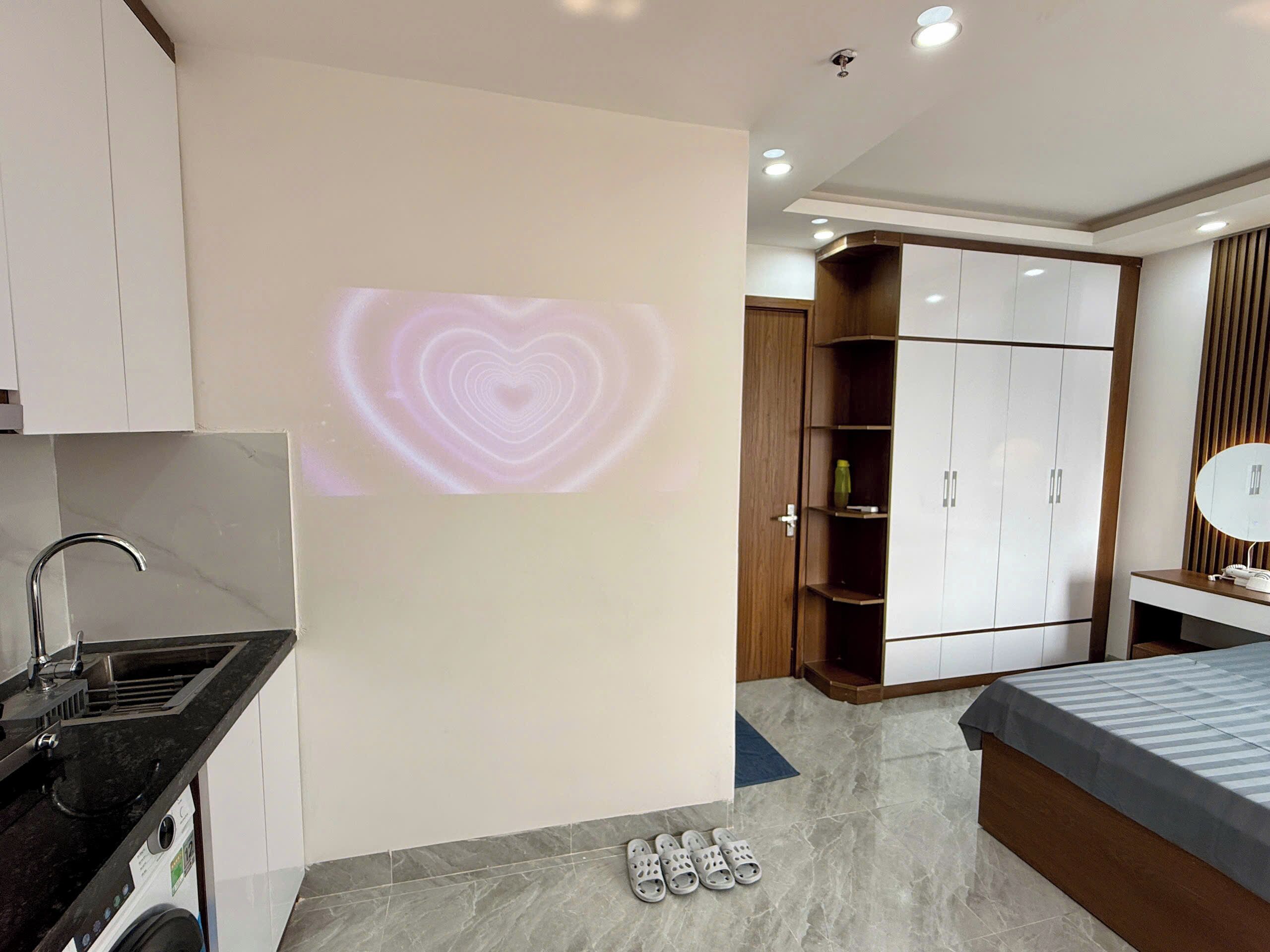 A modern bedroom with a bed, a wardrobe, and a bathroom with a sink.