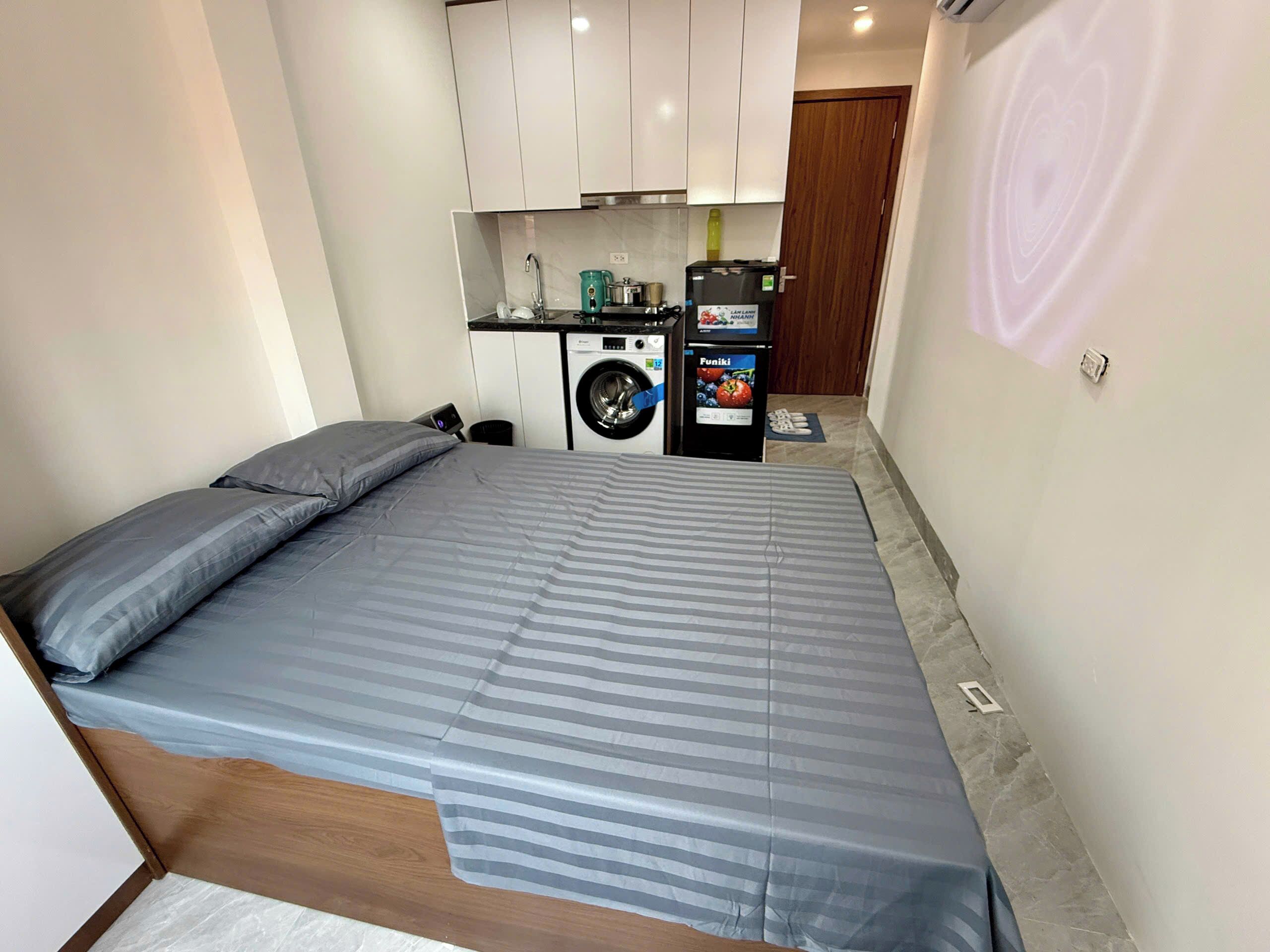Ein kleines Schlafzimmer mit Bett, Waschmaschine und einer kleinen Küchenzeile.