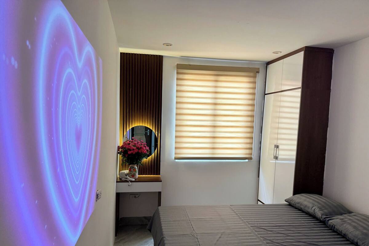 Un dormitorio con una cama, un escritorio con espejo y una ventana con persianas.