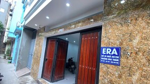 A building with a blue sign, a motorbike inside, and a paved entrance. - Era Apartment Hoang Hoa Tham (Hanoi)