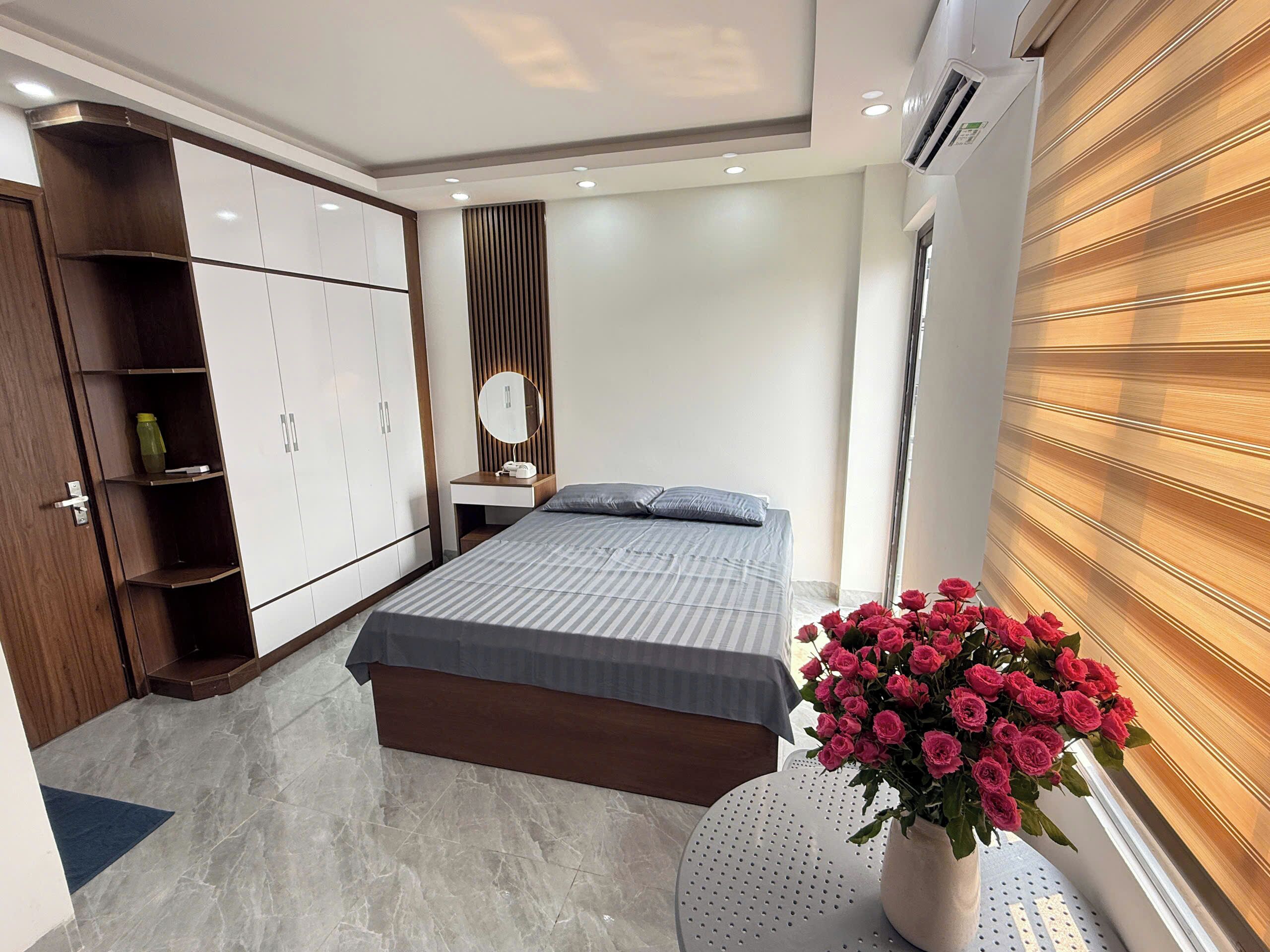 A bedroom with a bed, wardrobe, vanity, and a window with blinds.
