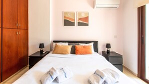 Een hotelkamer met een bed, twee nachtkastjes, een kledingkast en twee kunstwerken aan de muur.