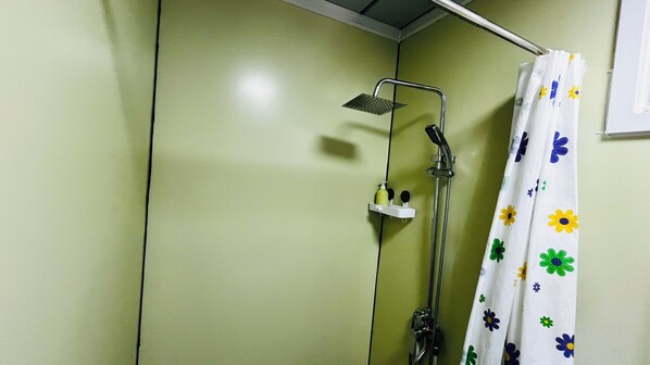 Eine Dusche mit Regendusche, Handbrause und einer Duschvorhang mit einem floralen Muster.