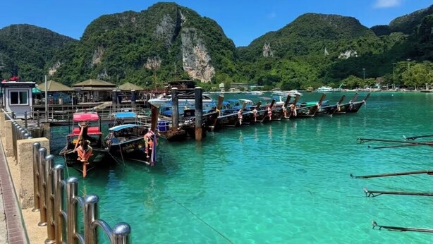A boat dock with clear turquoise water, a pier with metal railings, and lush green mountains in the background. - Smily Phuket Patong Sea View (Tambon Patong)