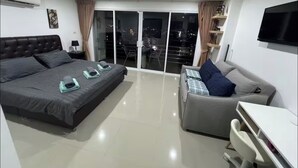 A modern bedroom with a large bed, a sofa, a desk, and a TV. - Smily Phuket Patong Sea View (Tambon Patong)