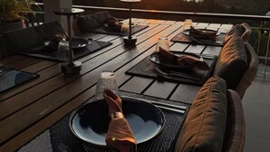A sunset view from a deck with outdoor seating and a dining table set for two. - Smily Phuket Patong Sea View (Tambon Patong)