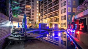 A hotel pool area with a water feature, surrounded by multi-story buildings. - Smily Phuket Patong Sea View (Tambon Patong)