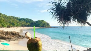 A beach view with a wooden railing, a coconut drink, and a clear blue sea. - Smily Phuket Patong Sea View (Tambon Patong)