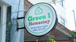 A circular sign with 'Green 1 Homestay' and contact information. - Green Homestay  (Da Nang)