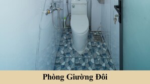 A bathroom with a toilet, shower, and a towel rack. - Green Homestay  (Da Nang)