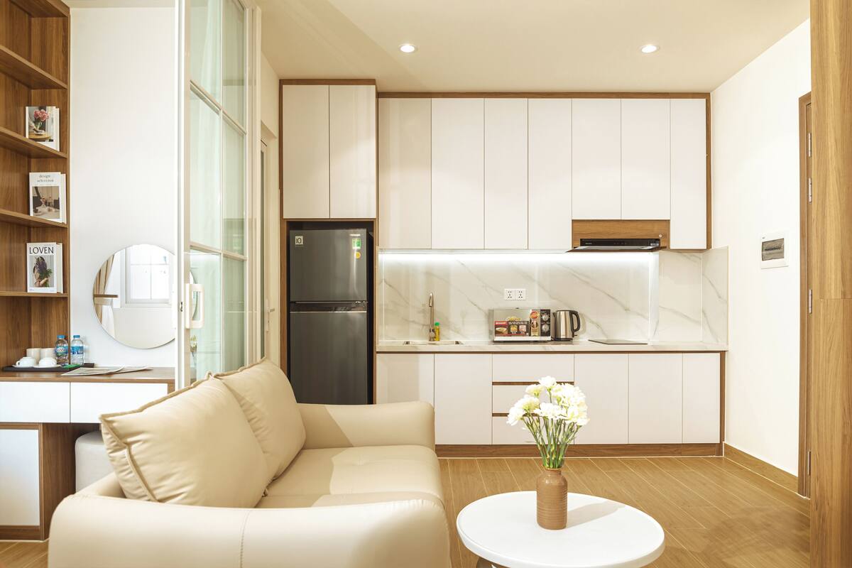 Una cucina moderna con mobili bianchi, forno integrato e frigorifero in acciaio inossidabile.