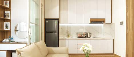 A modern kitchen with white cabinets, a built-in oven, and a stainless steel refrigerator.