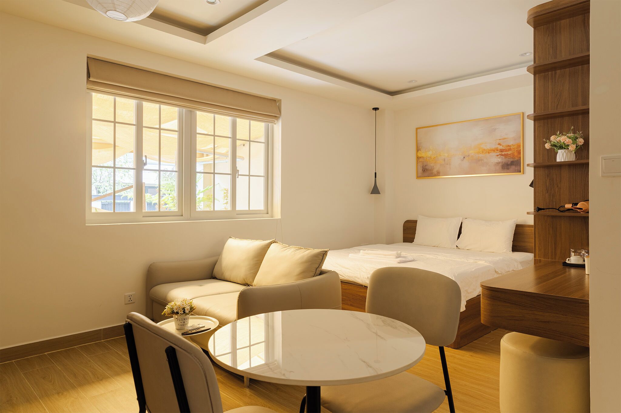 A hotel room with a bed, a sofa, a dining table, and a small kitchen area.
