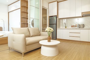 A modern kitchen with white cabinets, a stainless steel refrigerator, and a coffee maker on the countertop. - CHOWA HOME by DNM Hospitality (An Khanh)