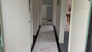 A narrow hallway with a patterned carpet, white walls, and a door at the end.